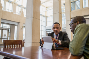 Two men at a table looking at a Microsoft Surface