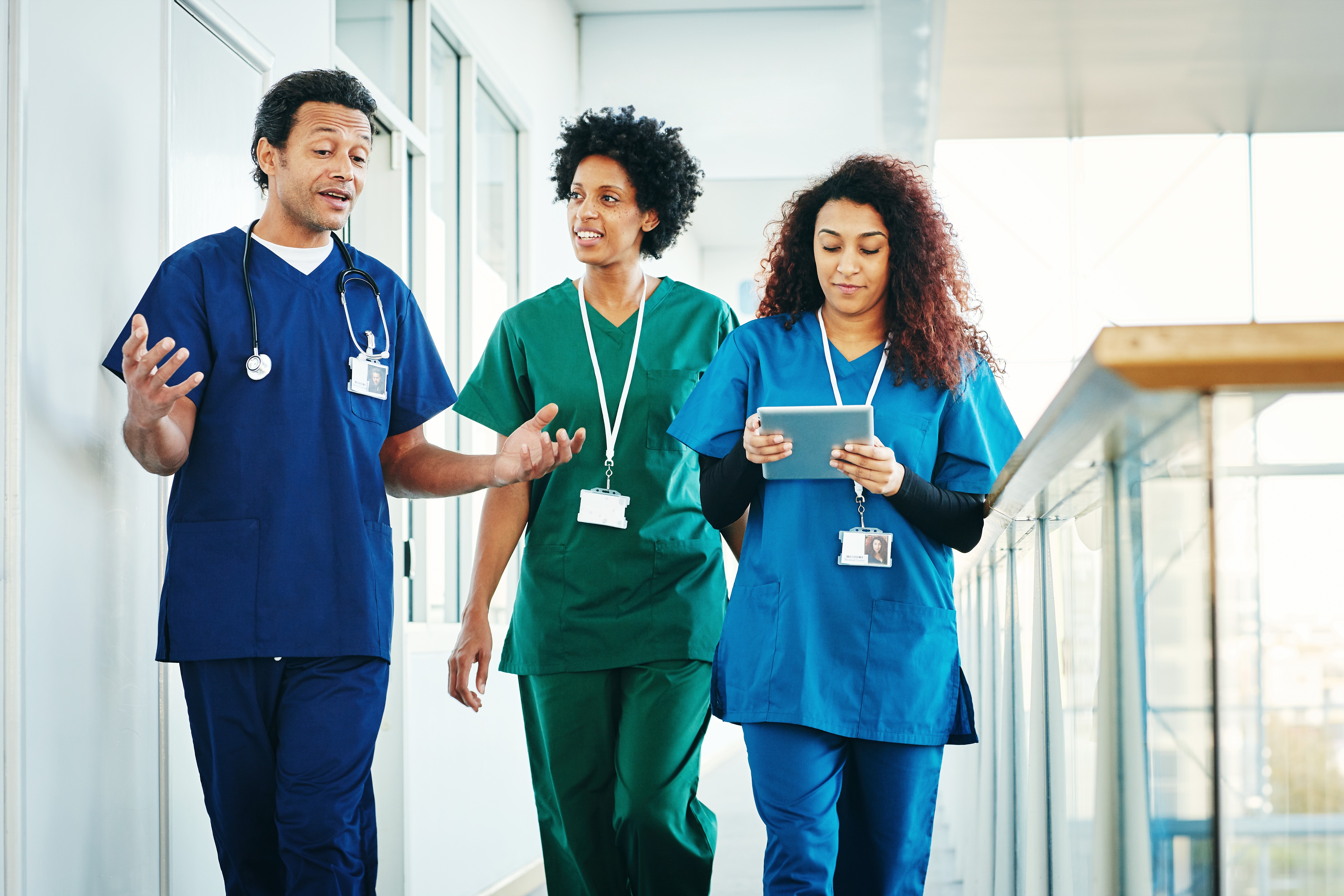 Group of medical professionals discussing while walking down hospital corridor