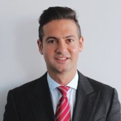 a man wearing a suit and tie smiling at the camera