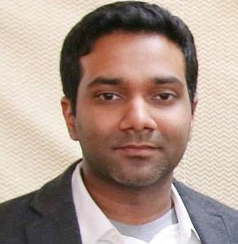a man wearing a suit and tie smiling at the camera