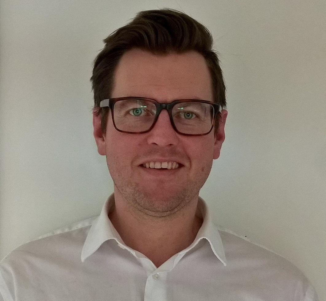 a man wearing glasses and smiling at the camera