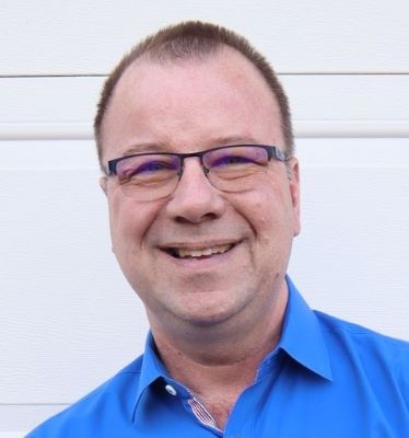 a man wearing glasses and smiling at the camera