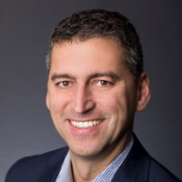 a man wearing a suit and tie smiling at the camera