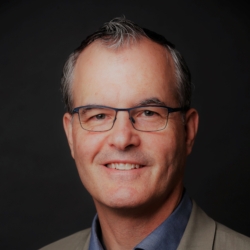 a man wearing glasses and smiling at the camera