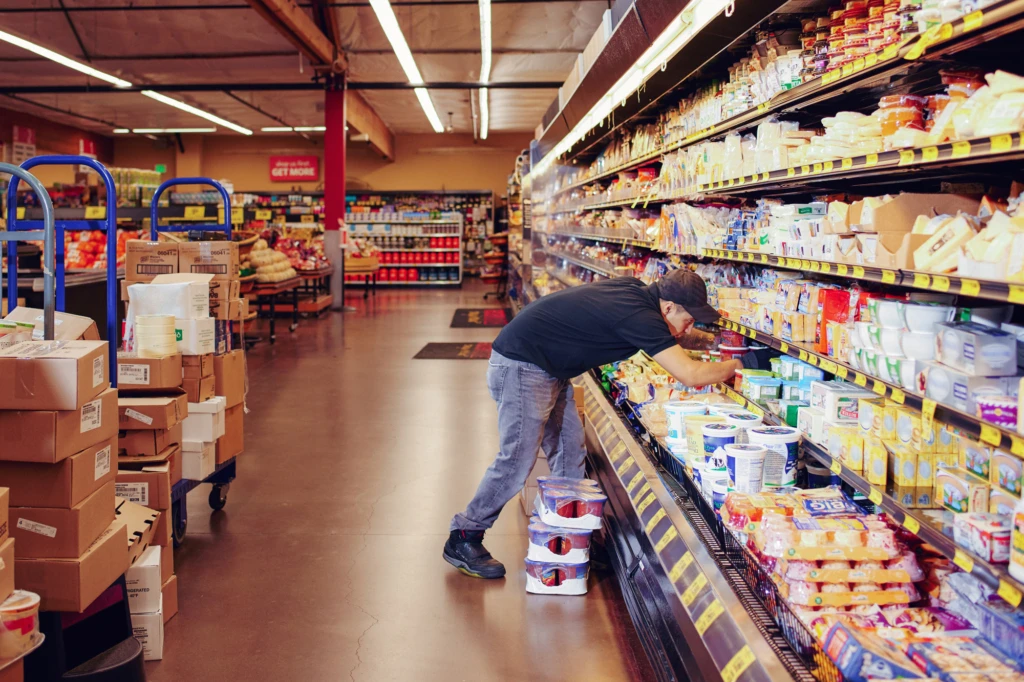 person stocking grocery store cooler shelves