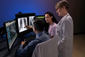 Three colleagues working together viewing chest x-rays.