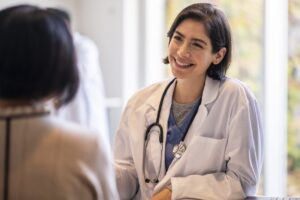 Female doctor smiling while sitting across from a senior patient.