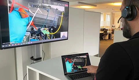 Ein Mann von hinten vor einem Tablet PC und einem großen Bildschirm an der Wand.