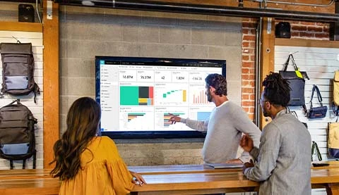 Ein Mann erklärt einer Frau und einem weiteren Mann etwas anhand Diagrammen.