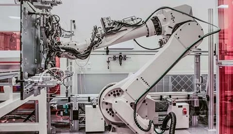 Ein weißer Industrieroboter, der gerade etwas Flaches hochhebt.