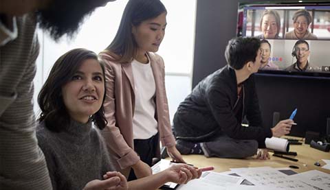 Mehrere Personen an einem Tisch bei einem hybriden Meeting