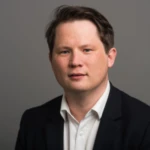 Henry Crawford, a man wearing a suit and tie smiling at the camera.