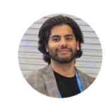 Hasan Javed, a man with dark hair and beard smiling at the camera.