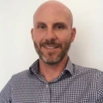 Mark Hawkins, a man in a checkered blue dress shirt smiling for the camera.