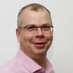 a man wearing glasses and smiling at the camera