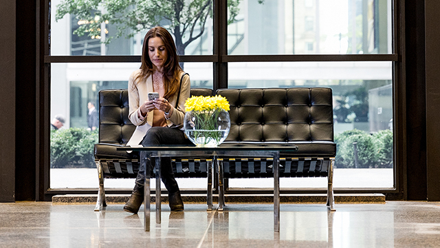 woman sitting on a black couch using her phone.
