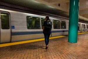 woman with a backpack waiting in the subway station in front of a moving train