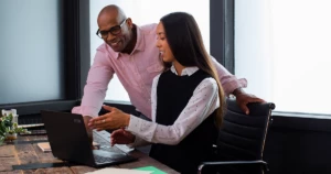 Small business employees collaborating in front of a laptop on a desk.