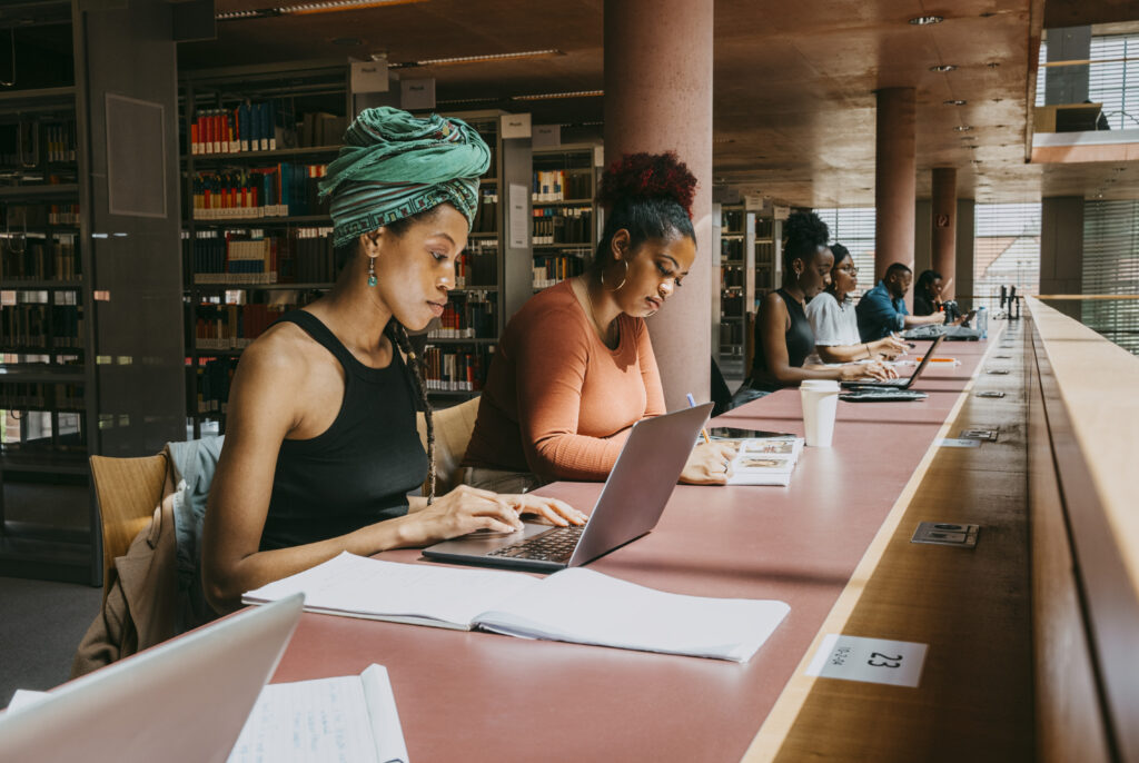 A group of women sitting at a table with laptops