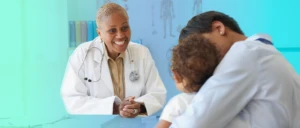 A doctor smiling at a child and parent