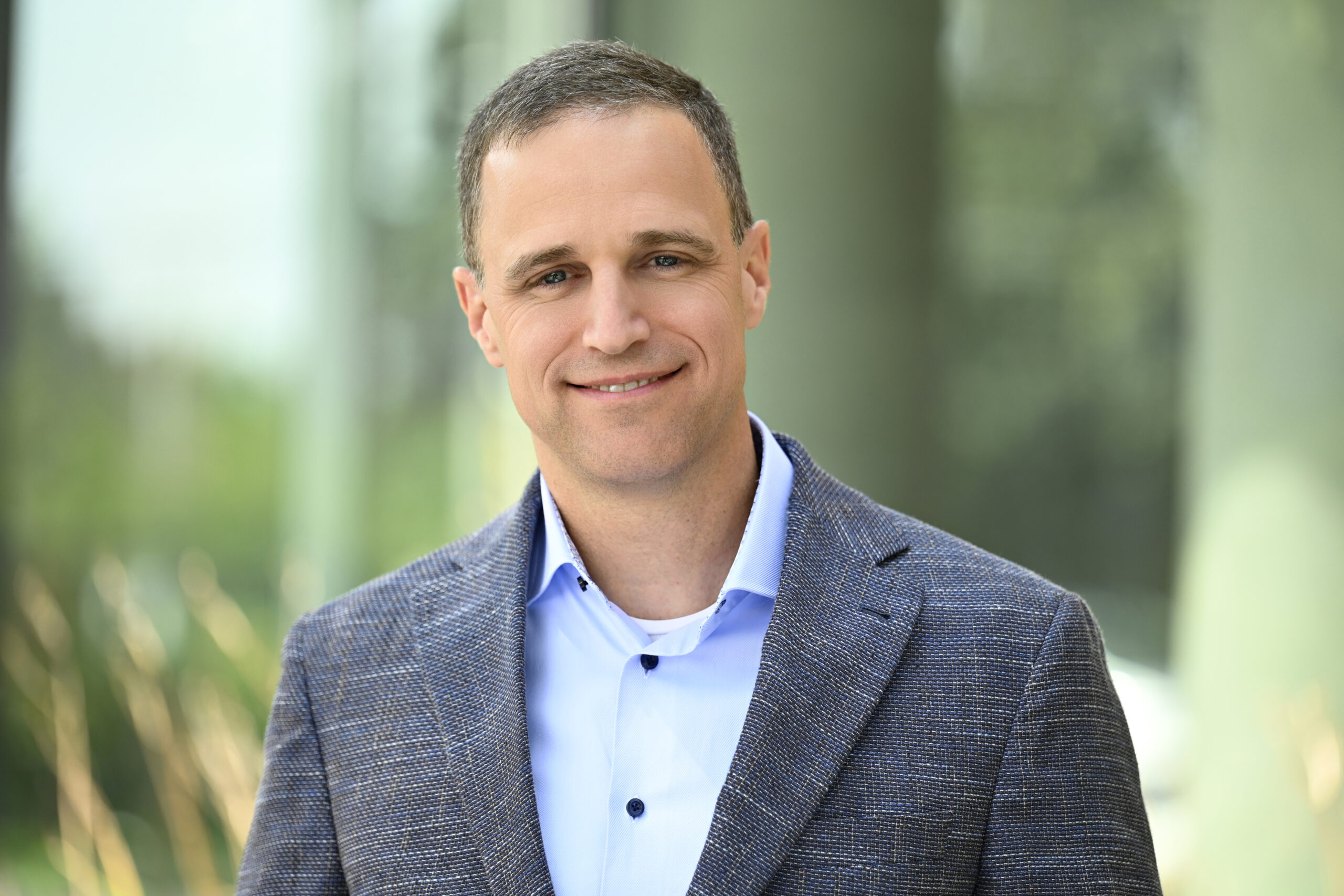 Person standing outdoors in a jacket and button‑down shirt