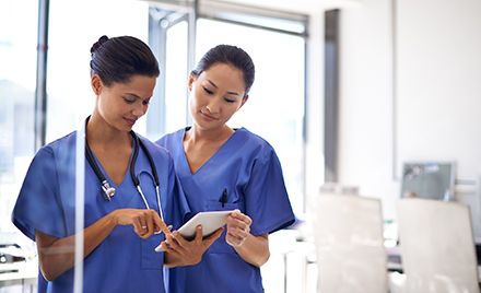 Shot of two female nurses using a tablet to review medical records