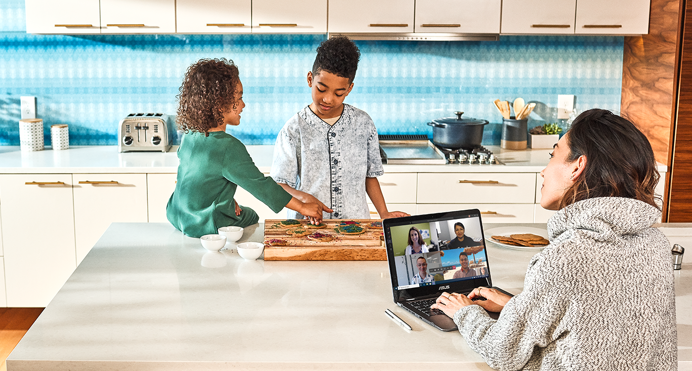 Image of a mother working from home, with her children at the kitchen countertop.