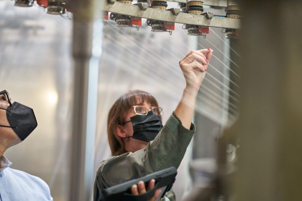 Masked adult woman working in factory.