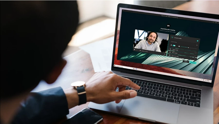 Person looking at a laptop screen that shows the join page of a Microsoft Teams meeting. The join page is customized with a branded background.