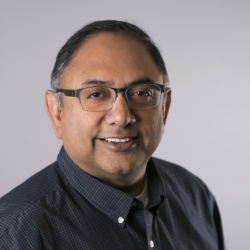 a man wearing glasses and smiling at the camera