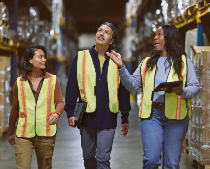 Warehouse workers walking through the aisle; manager reviewing and sharing data real time to make intelligent decisions powered by Azure.