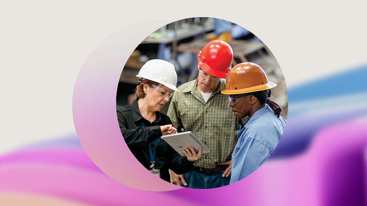 Three warehouse workers discuss over a tablet.