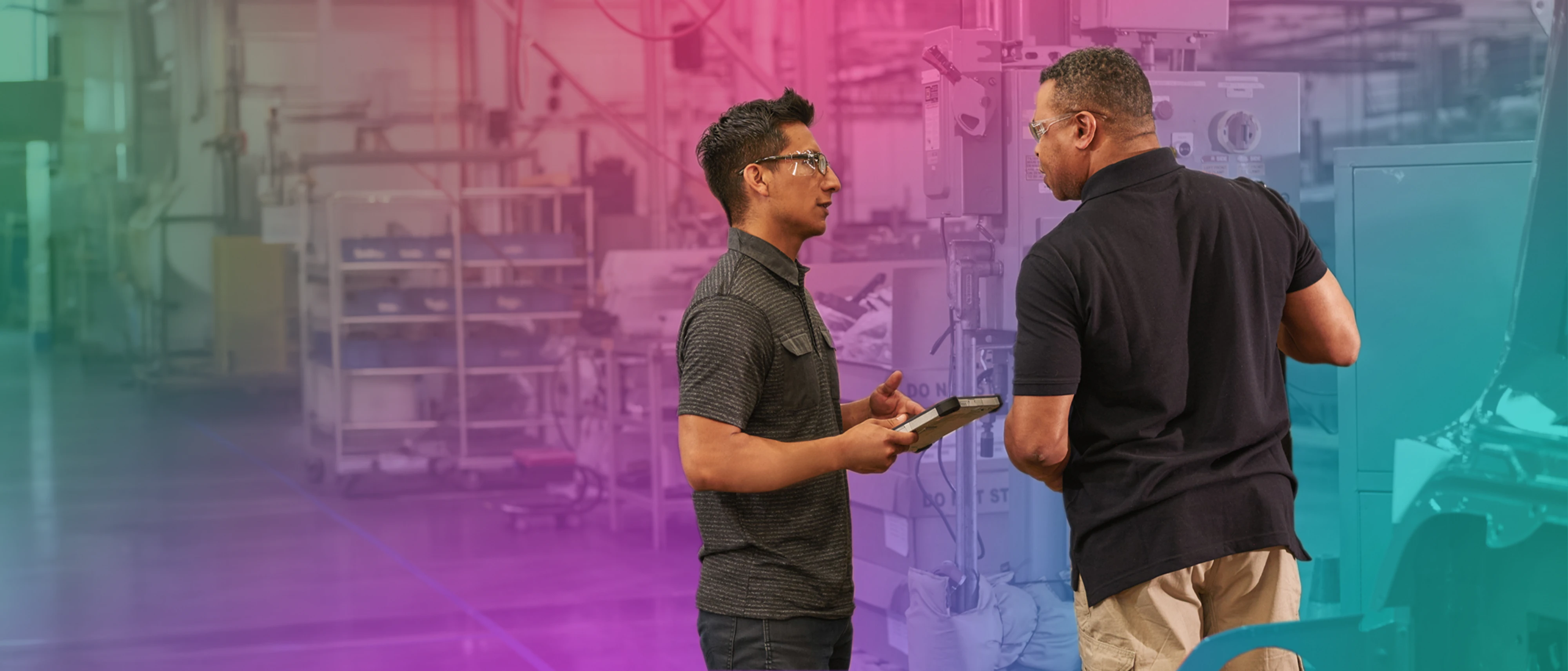 A man holding a tablet and talking to another man