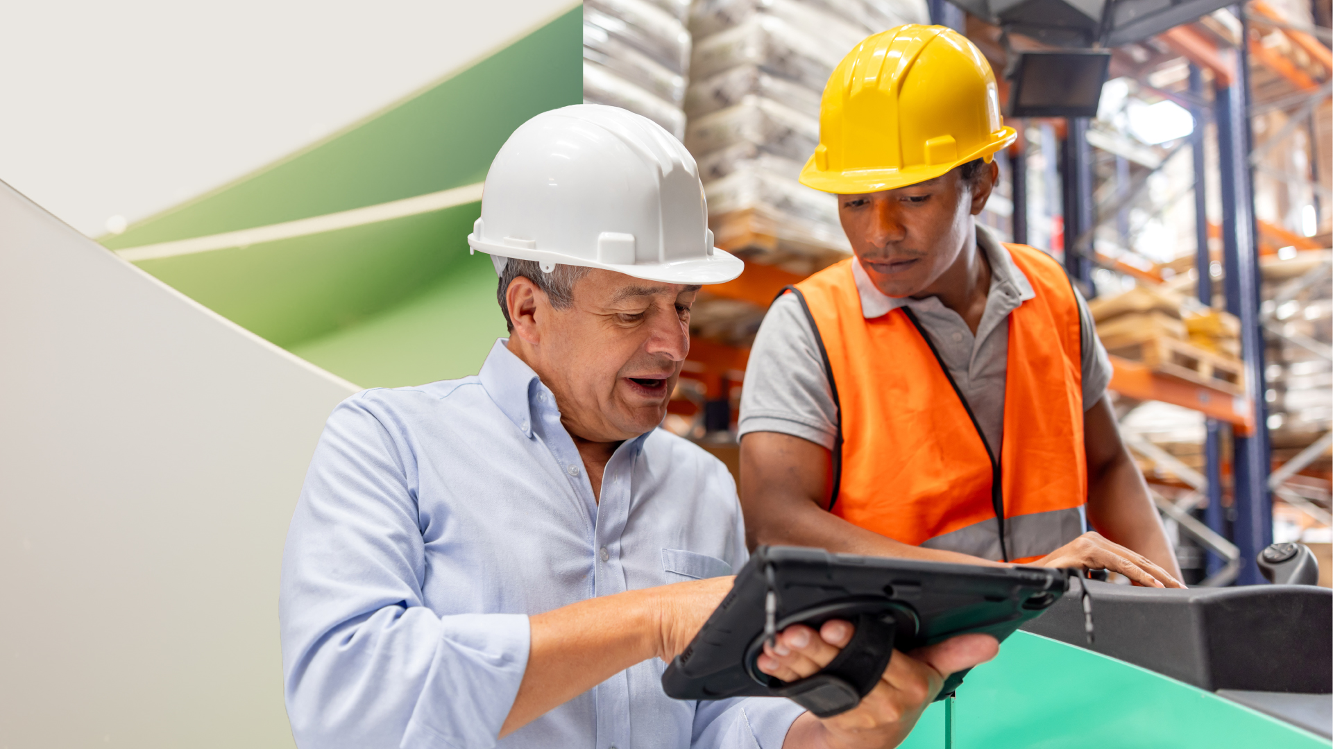 Two manufacturing professionals look over a tablet while on the job site.