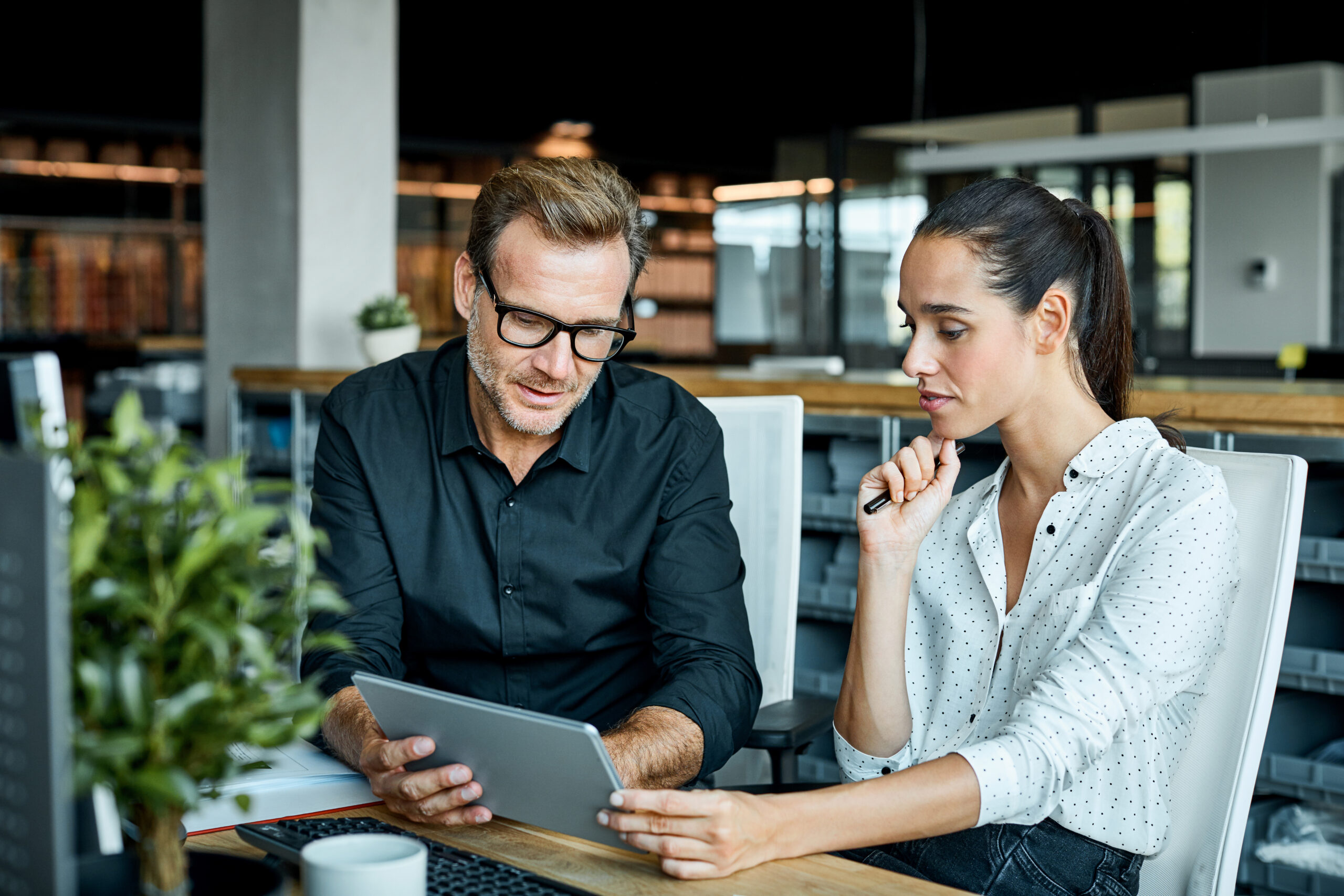 Two business people review documents on a tablet.