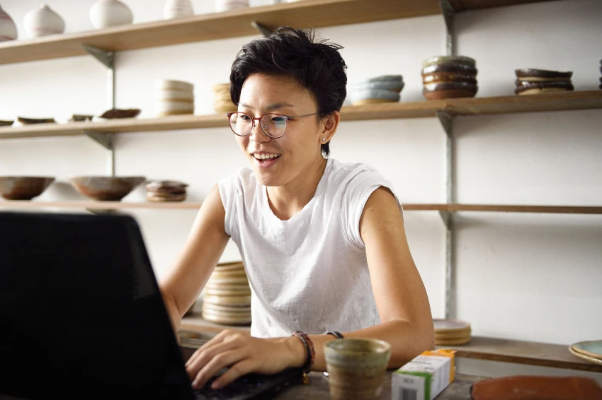 Decorative, a person working on a laptop in a pottery studio business. 