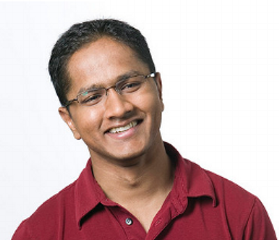 a man wearing glasses and smiling at the camera