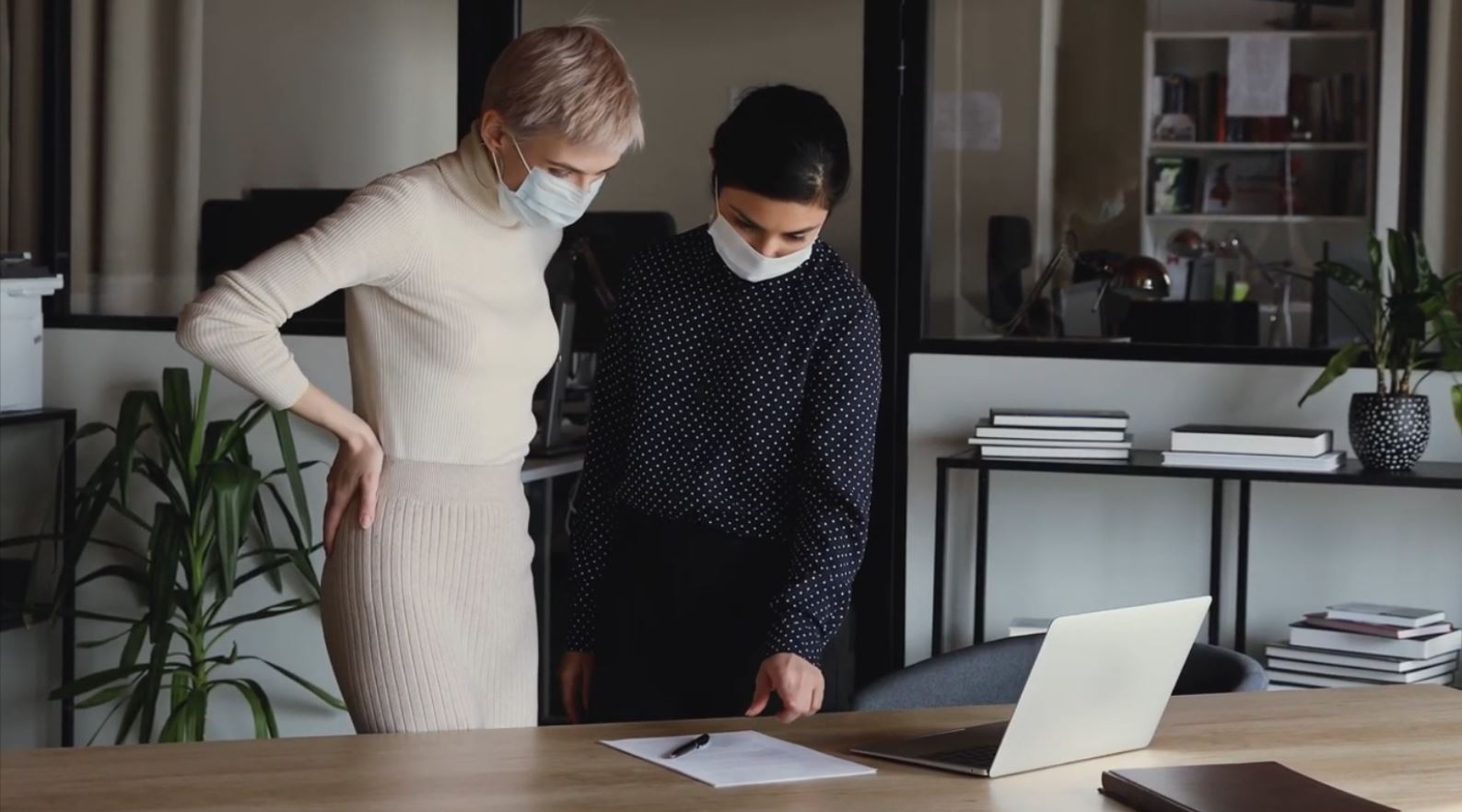 a woman standing in front of a laptop