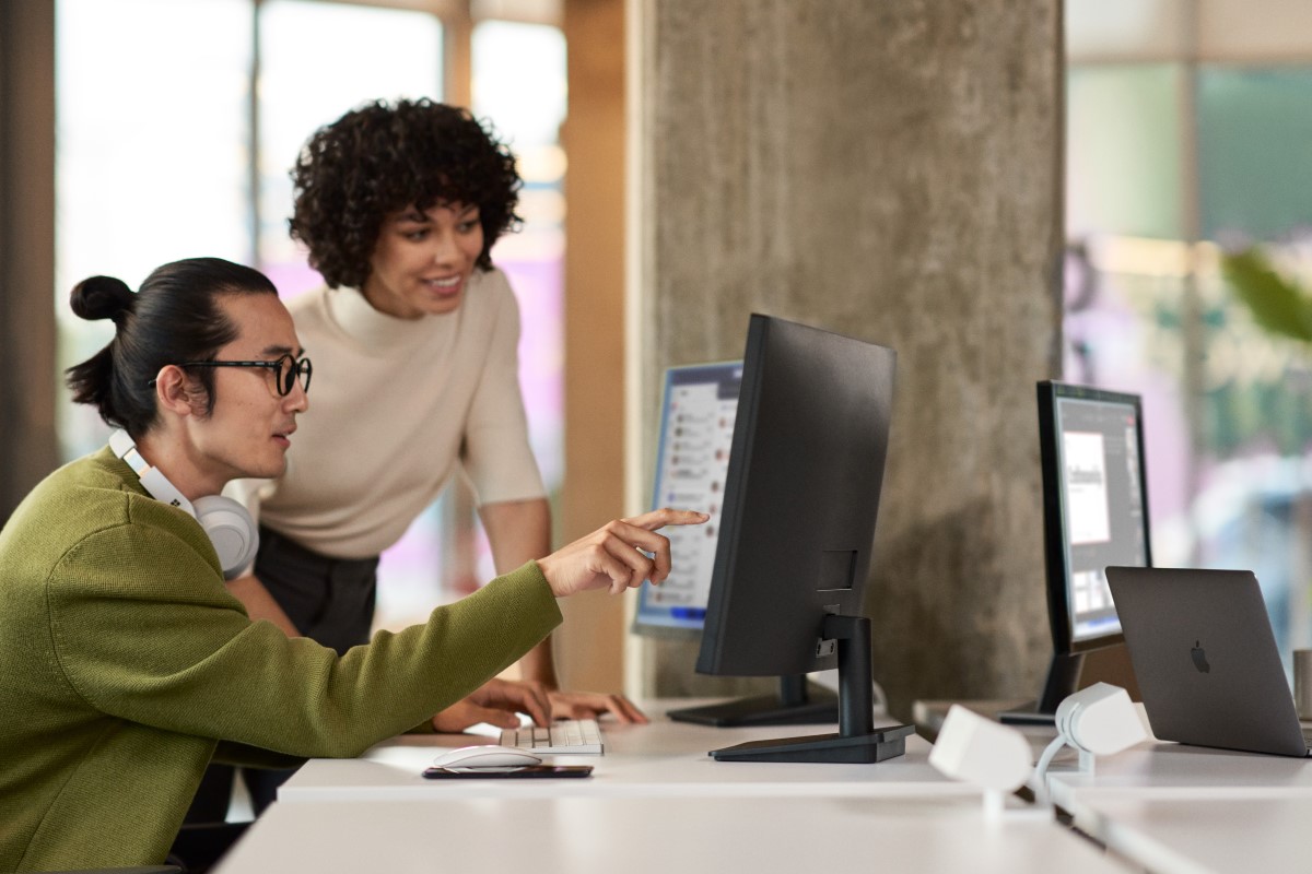 a woman showing a man something on the computer