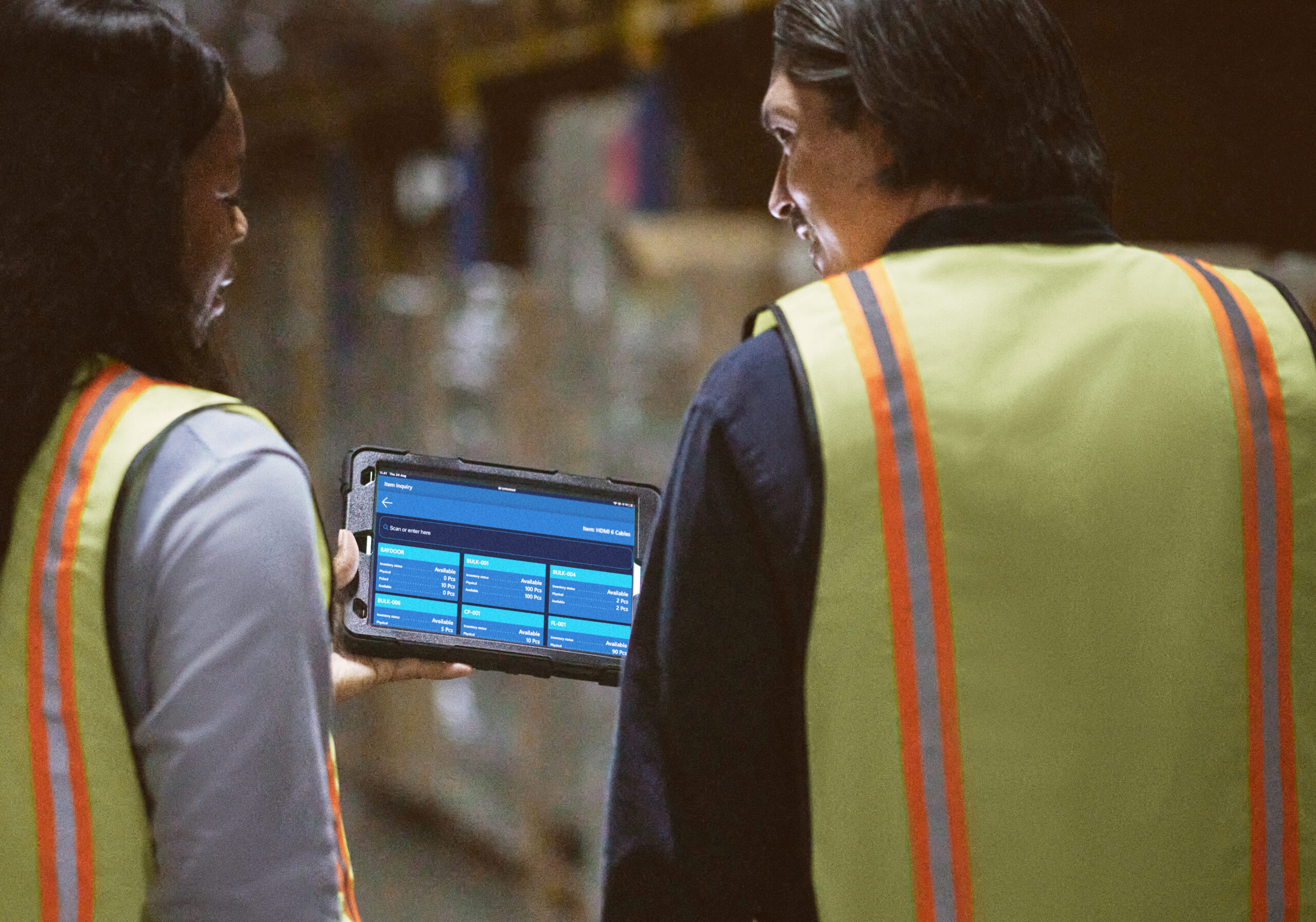 A man and woman in safety vests looking at a tablet