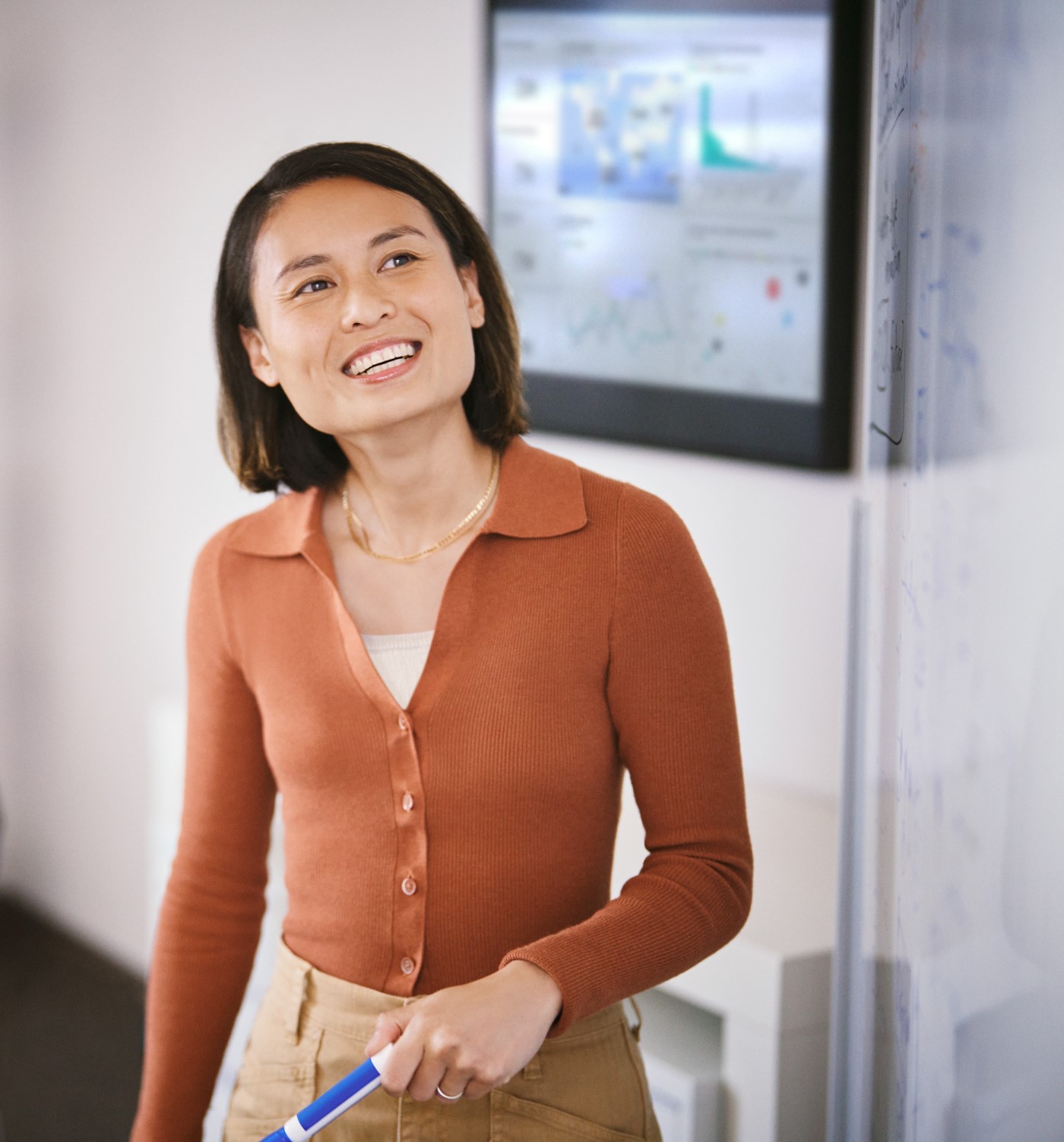A woman smiling and holding a pen