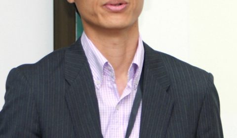 a man wearing a suit and tie smiling at the camera