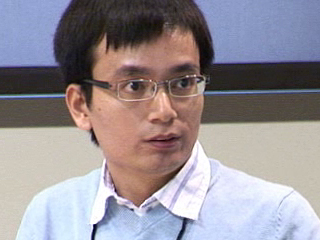 a man wearing glasses and smiling at the camera