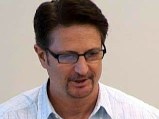 a man wearing glasses and smiling at the camera