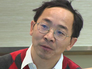 a man wearing a suit and tie smiling at the camera