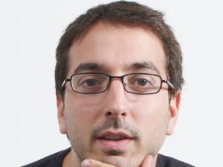 George Danezis wearing glasses and smiling at the camera