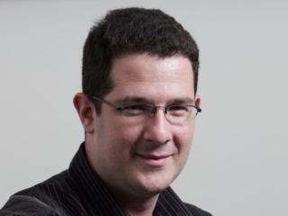 a man wearing glasses and smiling at the camera