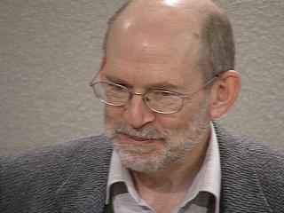 a man wearing glasses and smiling at the camera