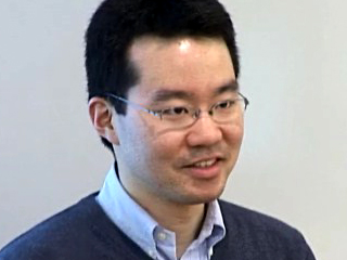 a man wearing a suit and tie smiling at the camera