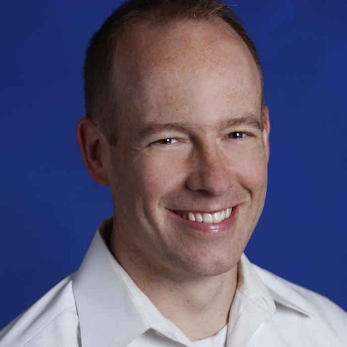 Doug Burger wearing a suit and tie smiling at the camera